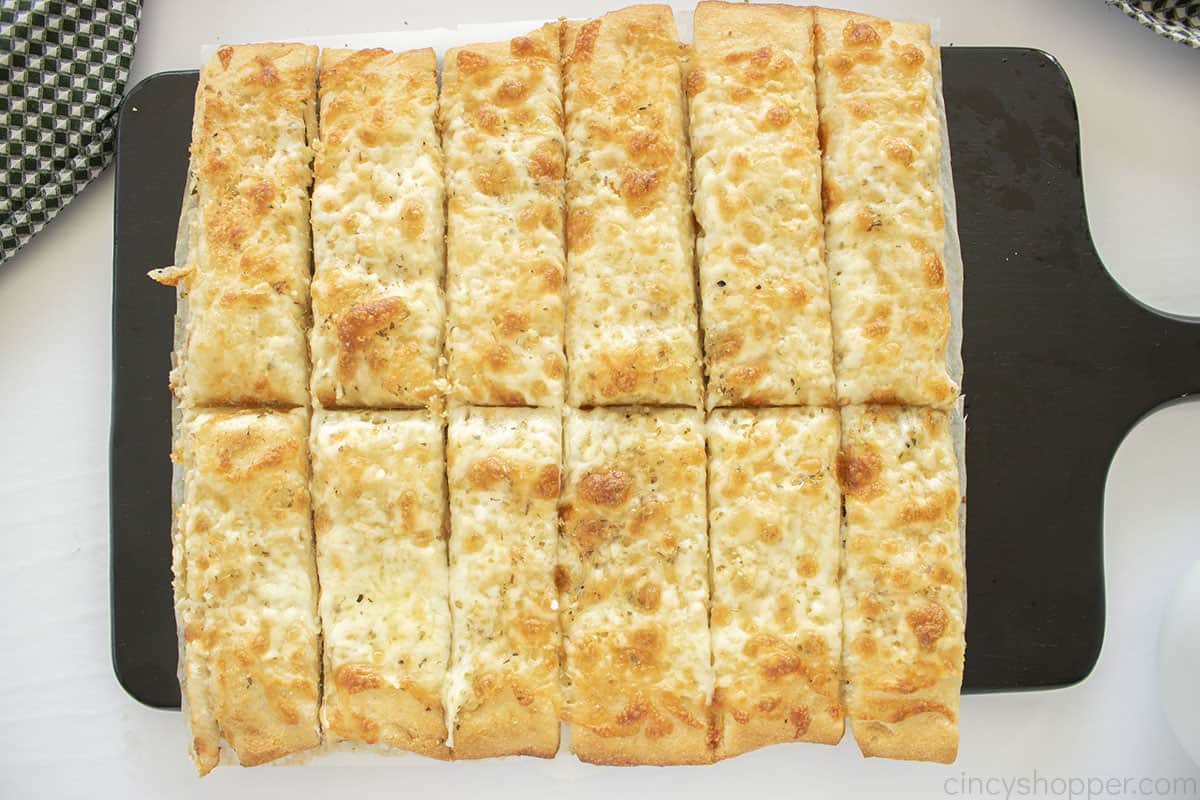 Homemade Cheese sticks on a black cutting board.