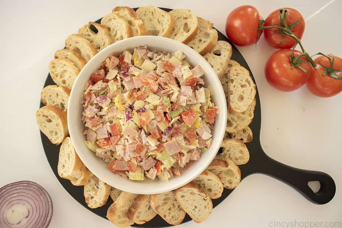 Italian Hoagie Dip in a white bowl with sliced bread pieces.