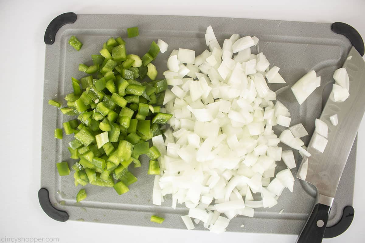 Diced onions and green peppers on a cutting board.