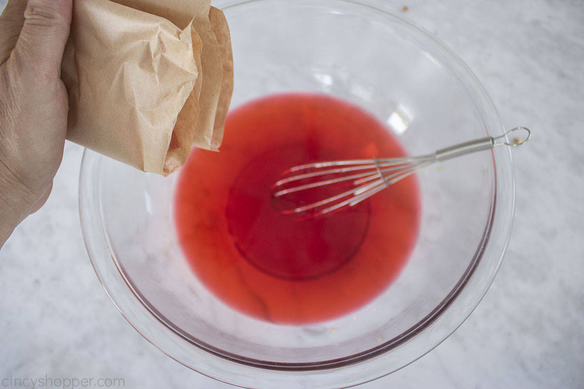 Adding powdered Jello to hot water.