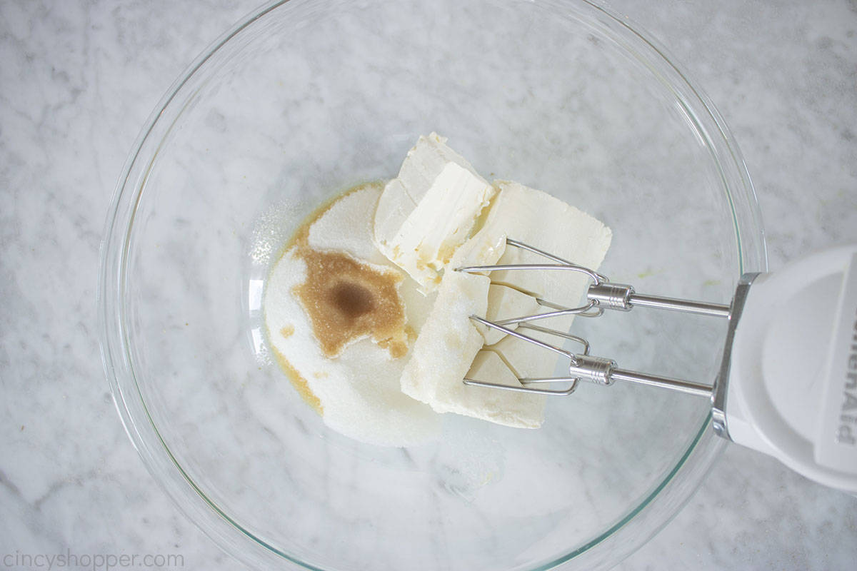 Cream cheese, sugar and vanilla in a bowl with a mixer.