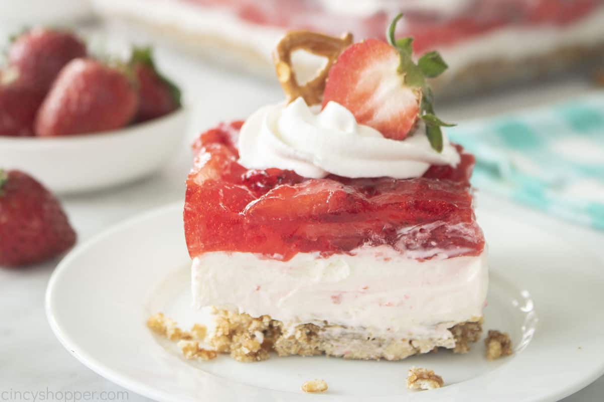 Piece of Strawberry Salad with strawberry and pretzel on top.