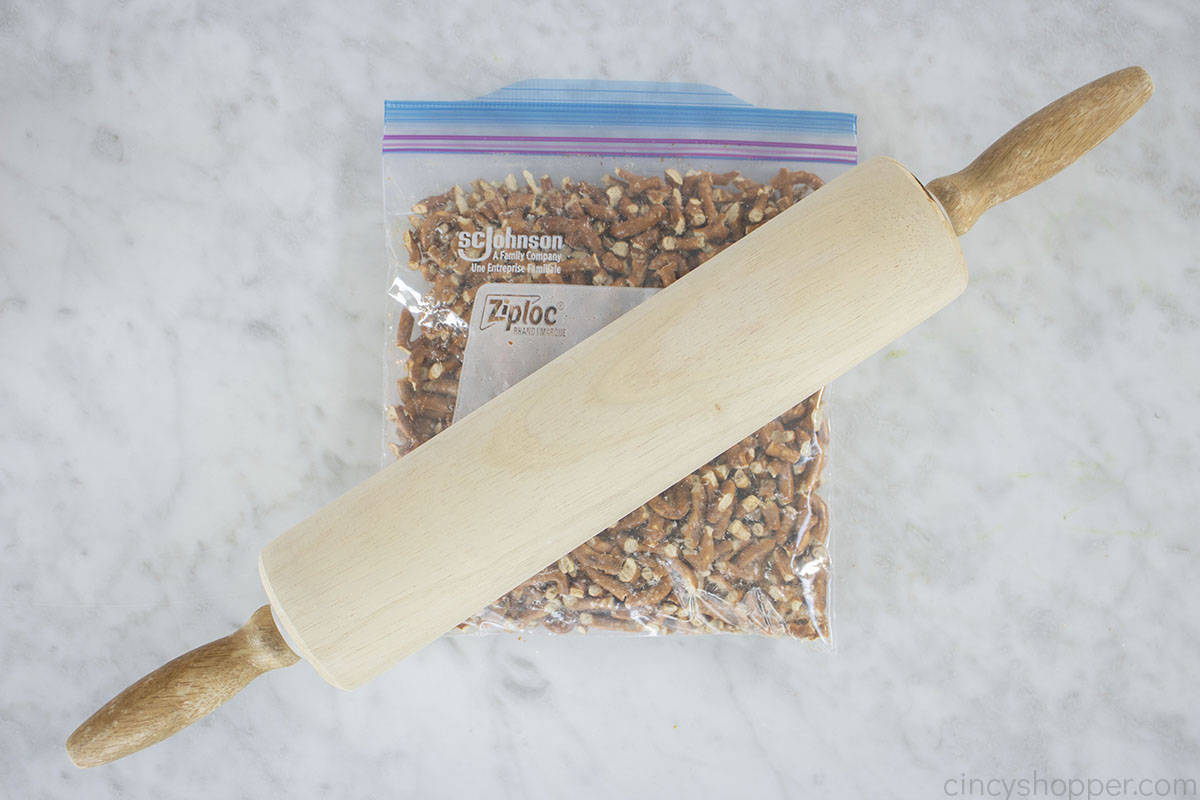 Crushing pretzels with a rolling pin.