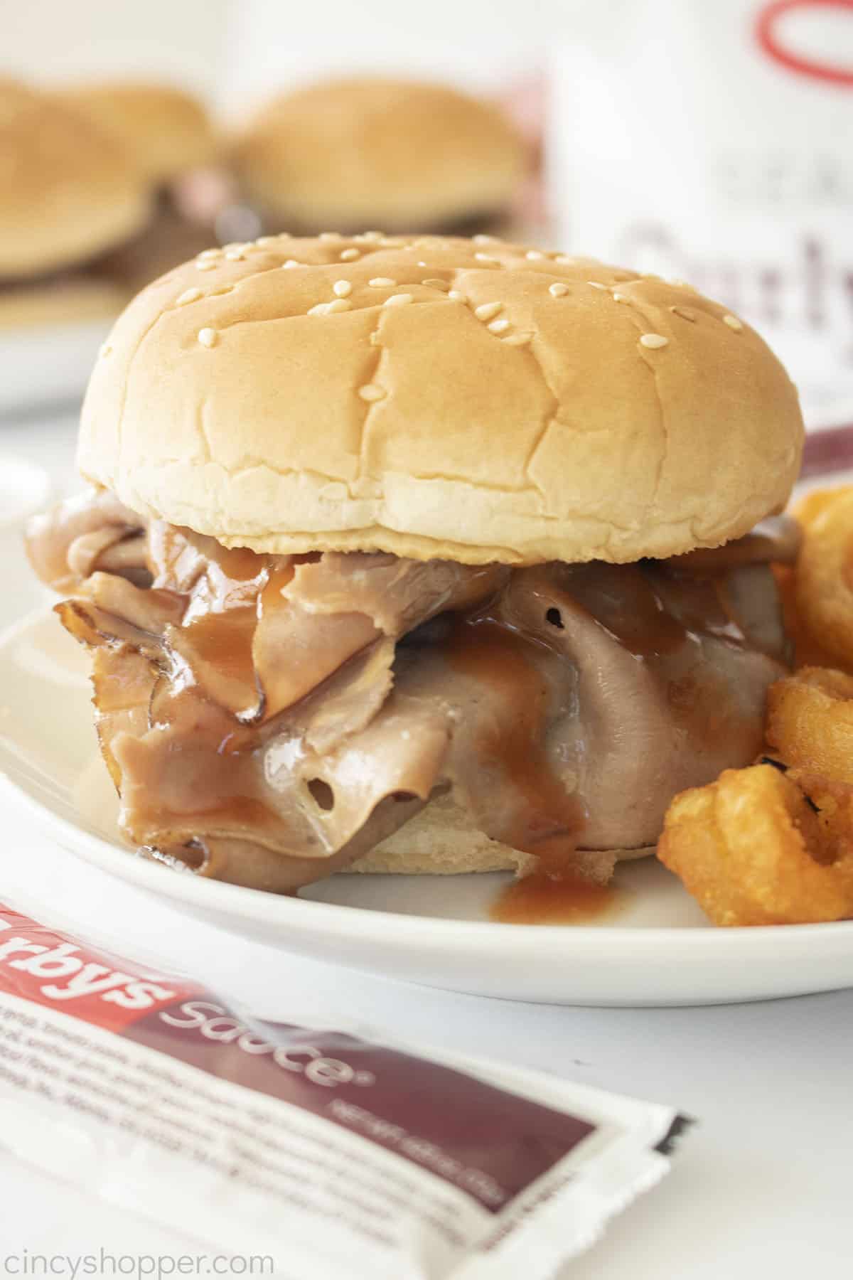 CopyCat Arby's Roast Beef Sandwich with sauce on a white plate.