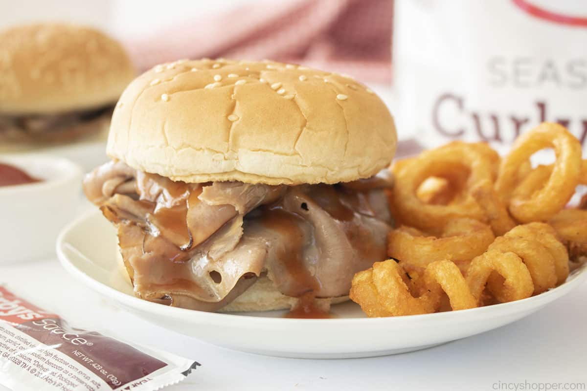 CopyCat Arby's Classic Roast Beef Sandwich with red sauce on a plate with curly fries.