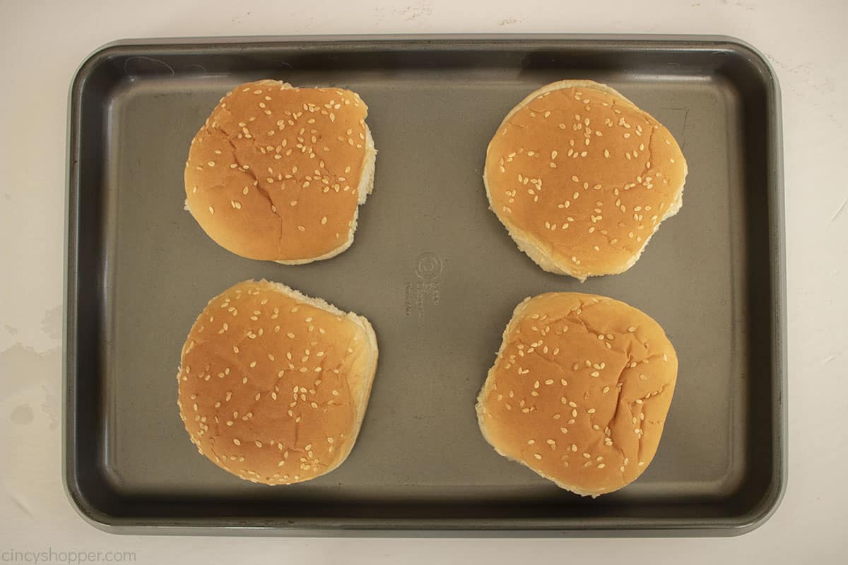 Sesame seed buns on a baking sheet.