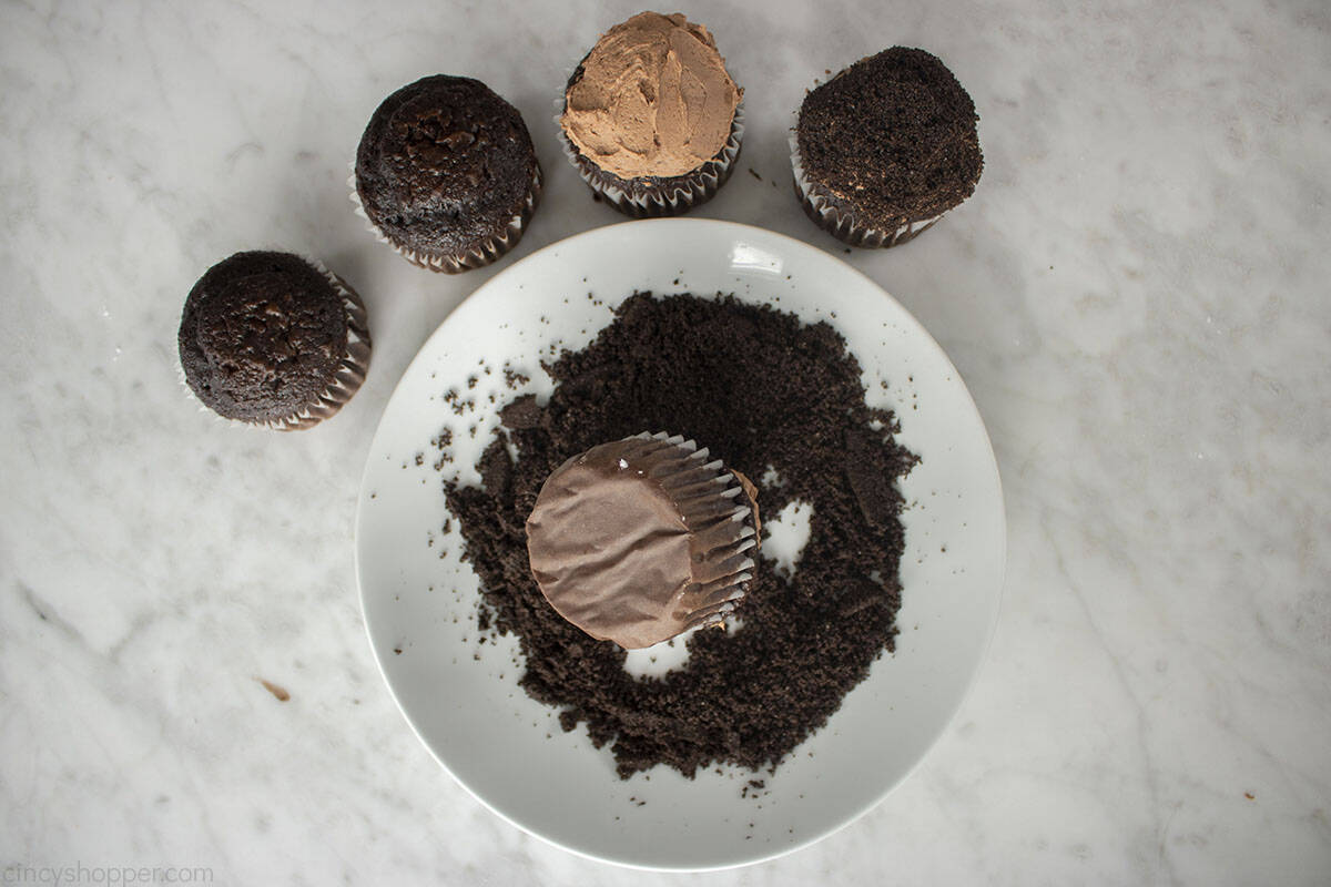 Topping cupcakes with frosting and crushed Oreo Cookies.