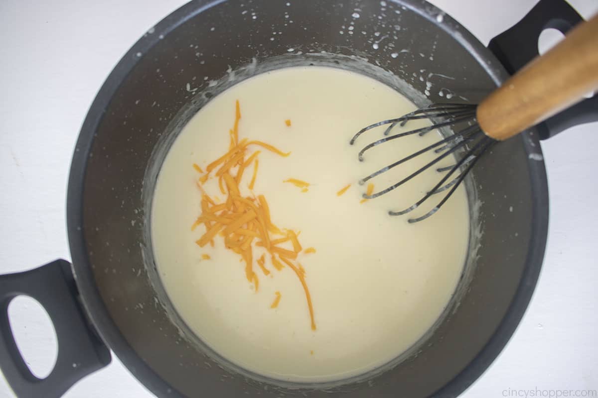 Slowly adding cheese to roux mixture.