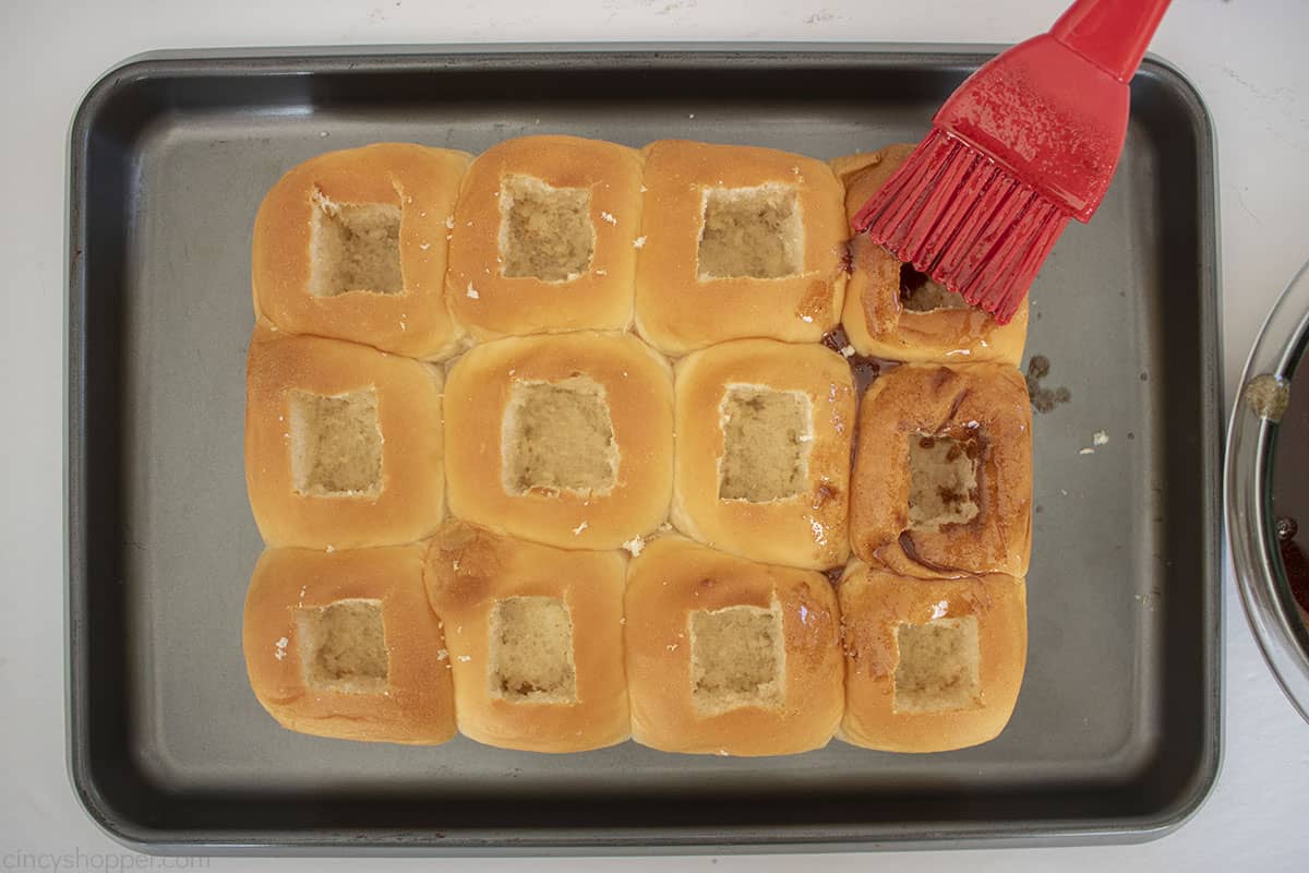 Brushing King's Hawaiian Rolls with cinnamon sugar butter.