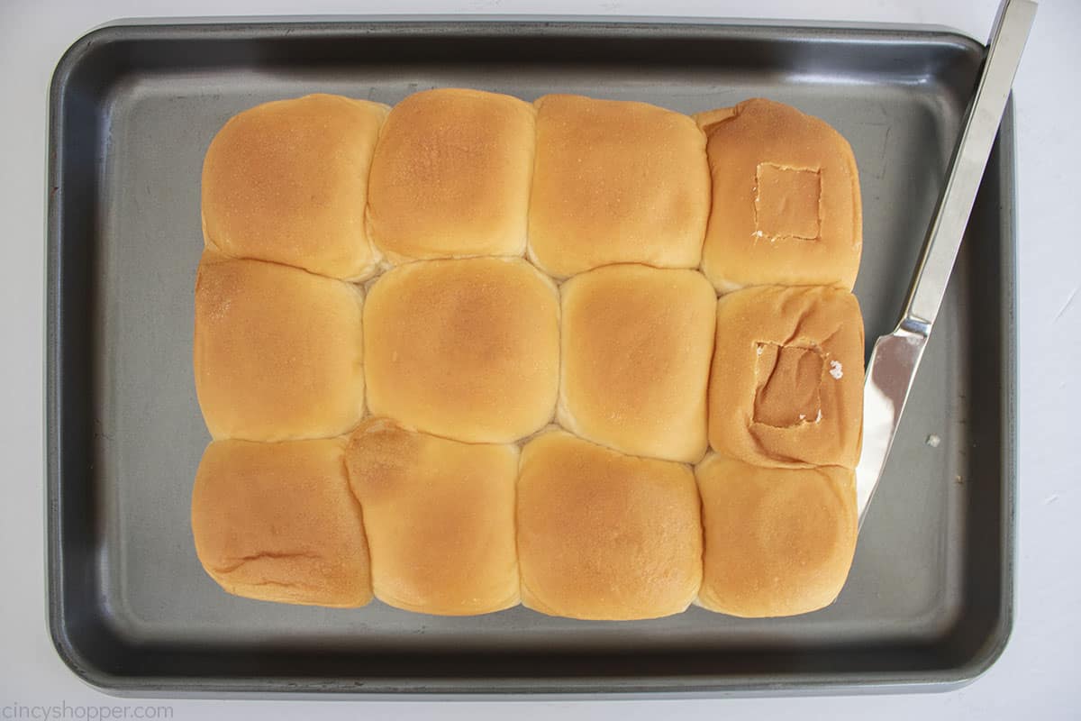 Slider rolls on a baking sheet with knife.