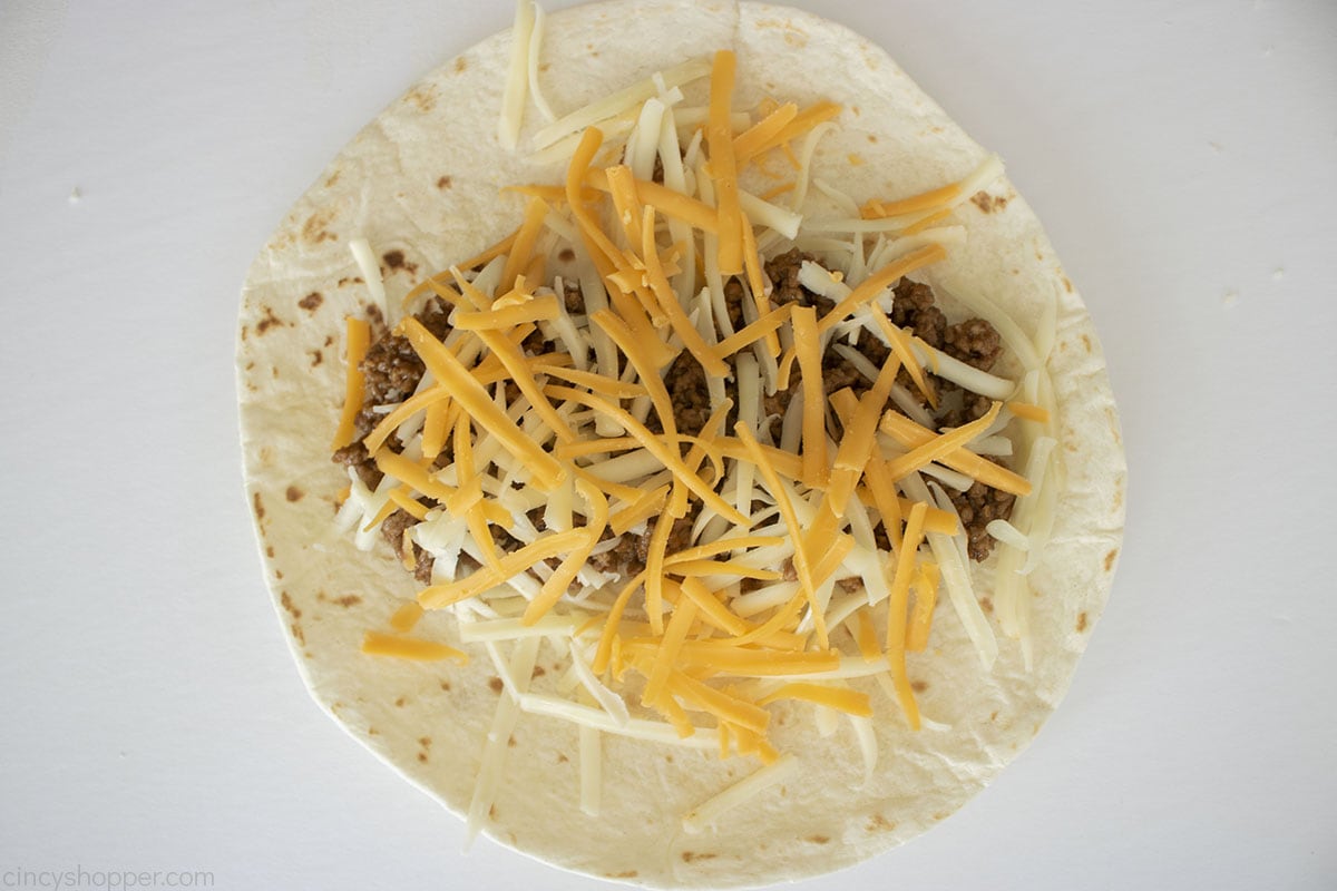 Three cheeses added to the top of ground beef soft taco.