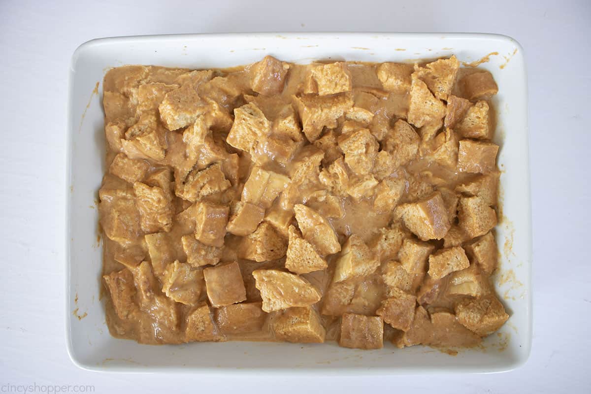 Pumpkin custard added to baking dish with cubed bread.