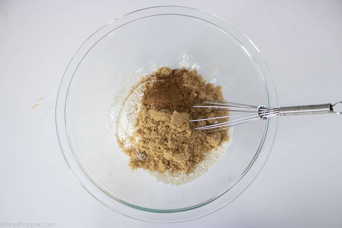 Streusel topping in a clear mixing bowl with a whisk.