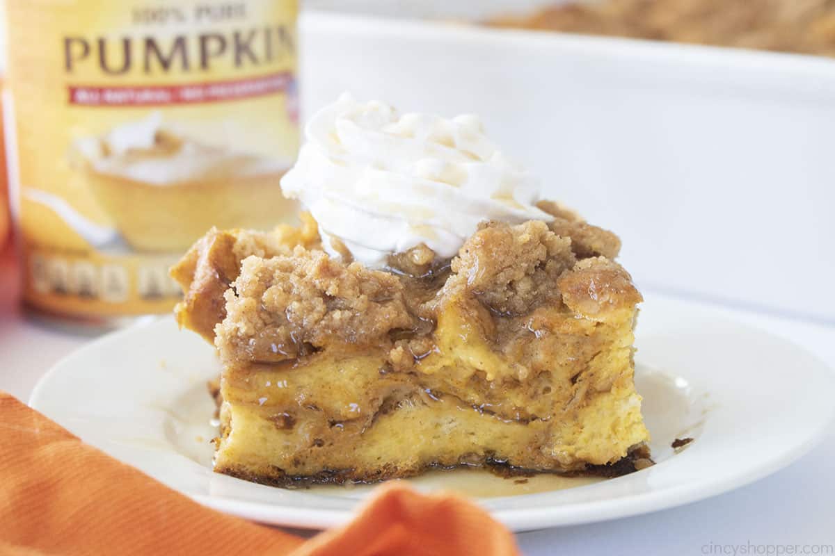 Slice of Pumpkin French Toast Casserole topped with syrup and whipped cream.