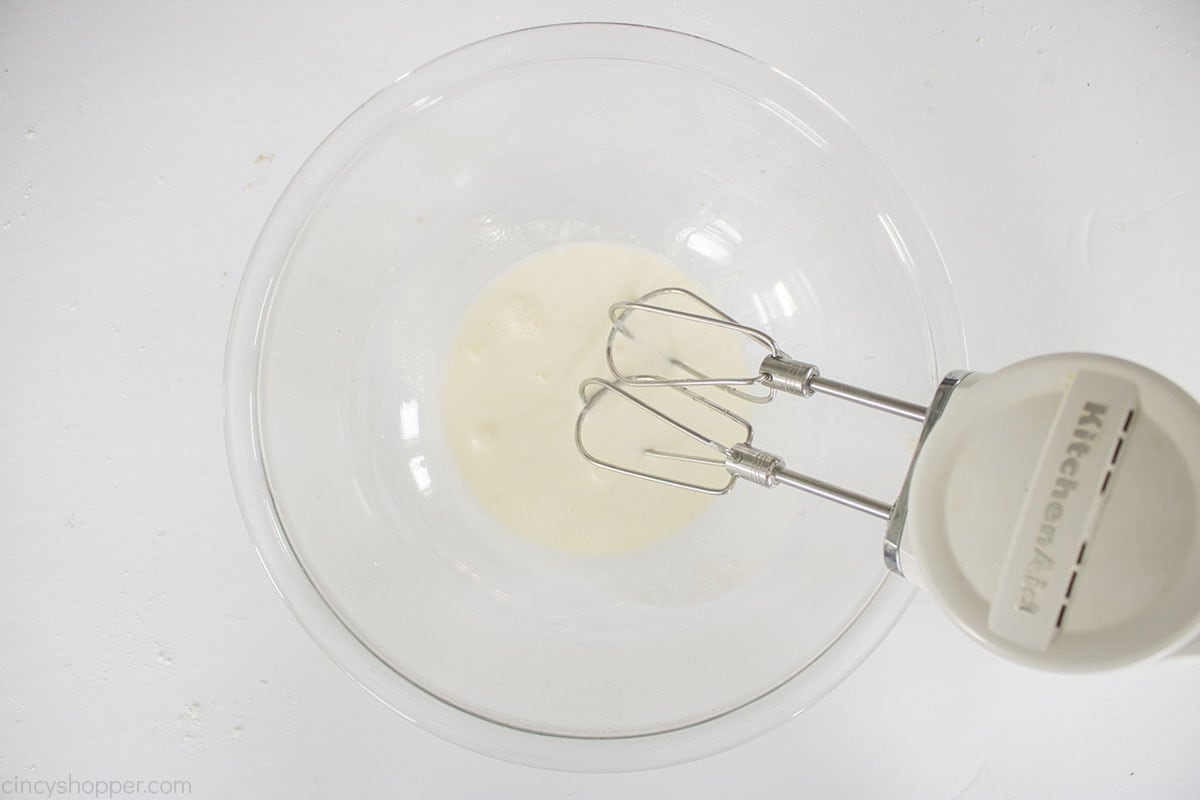 Heavy whipping cream in a bowl with hand mixer.