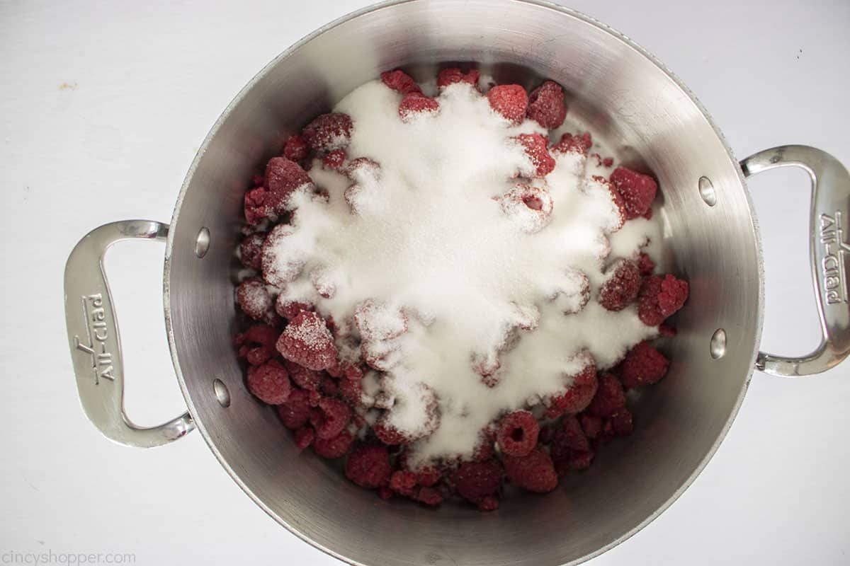 Raspberries and sugar in a pan.