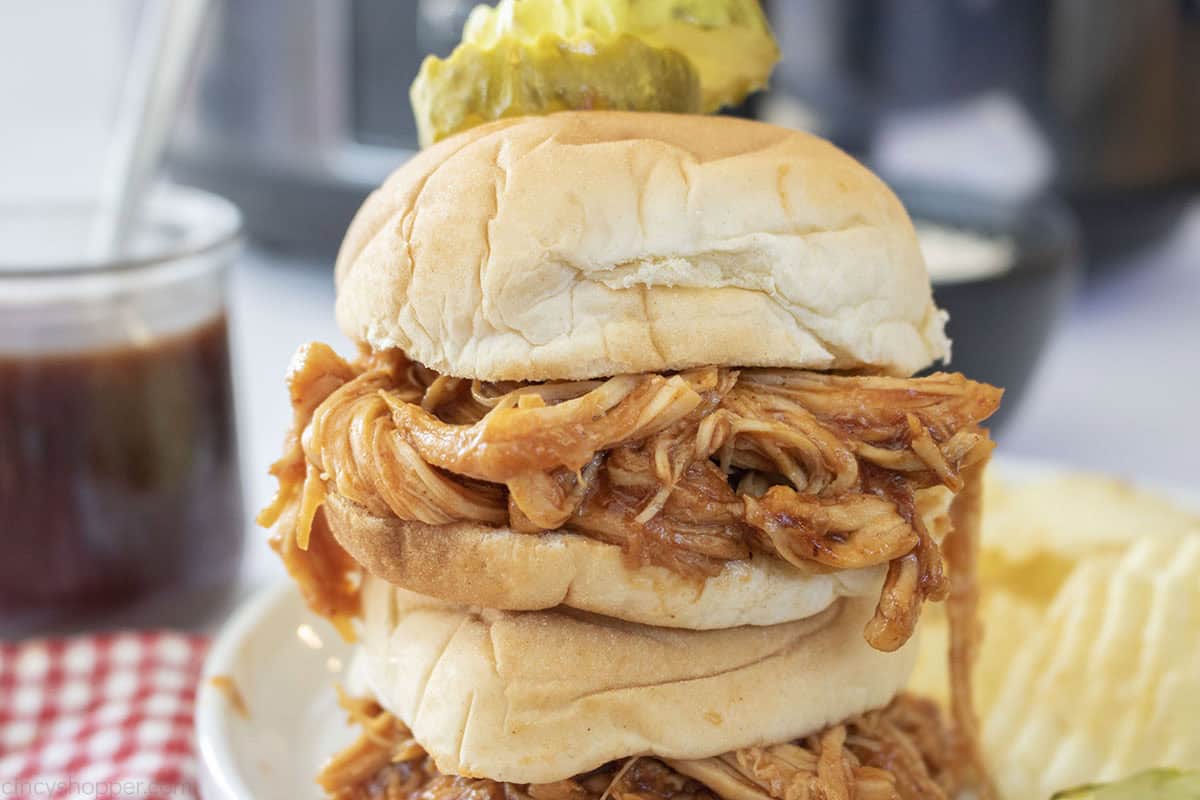 Stack of Slider Chicken sandwiches with a pickle and chips.