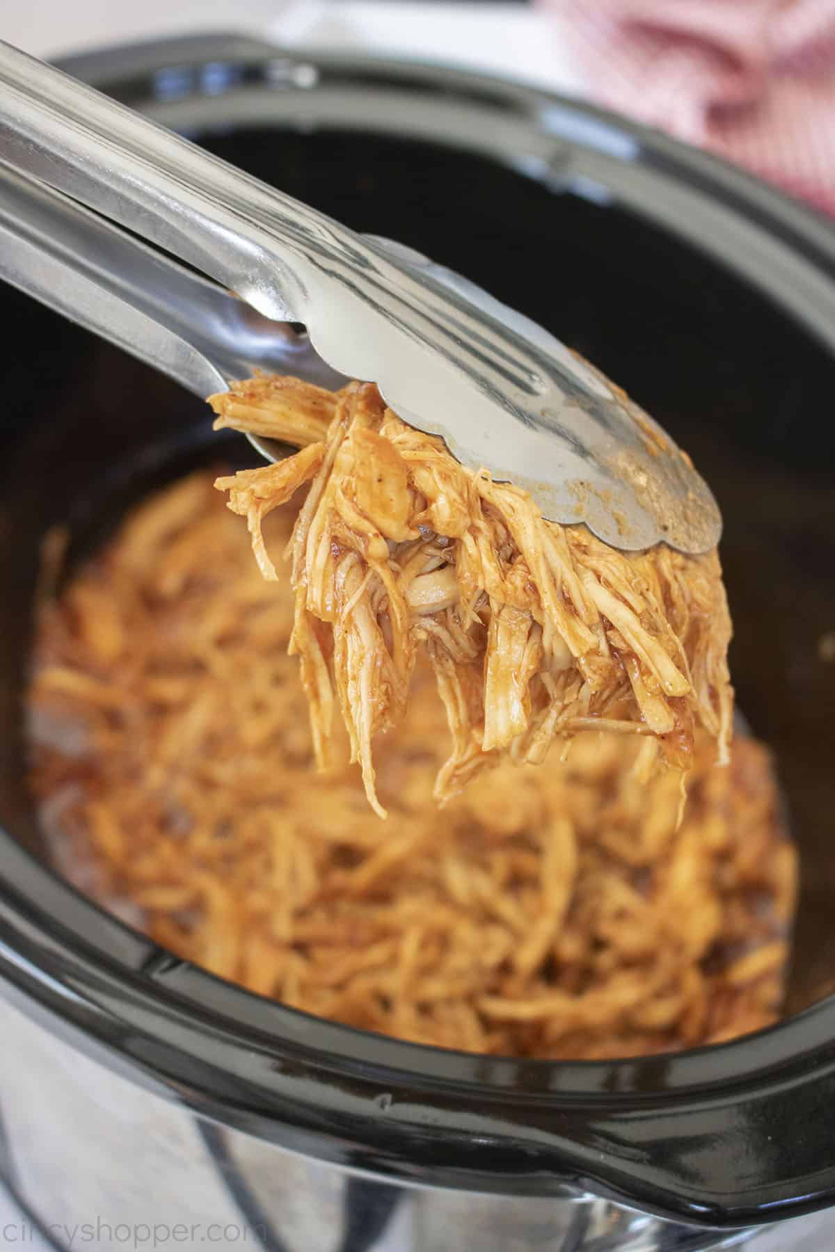 Slow Cooker BBQ Pulled Chicken on tongs.