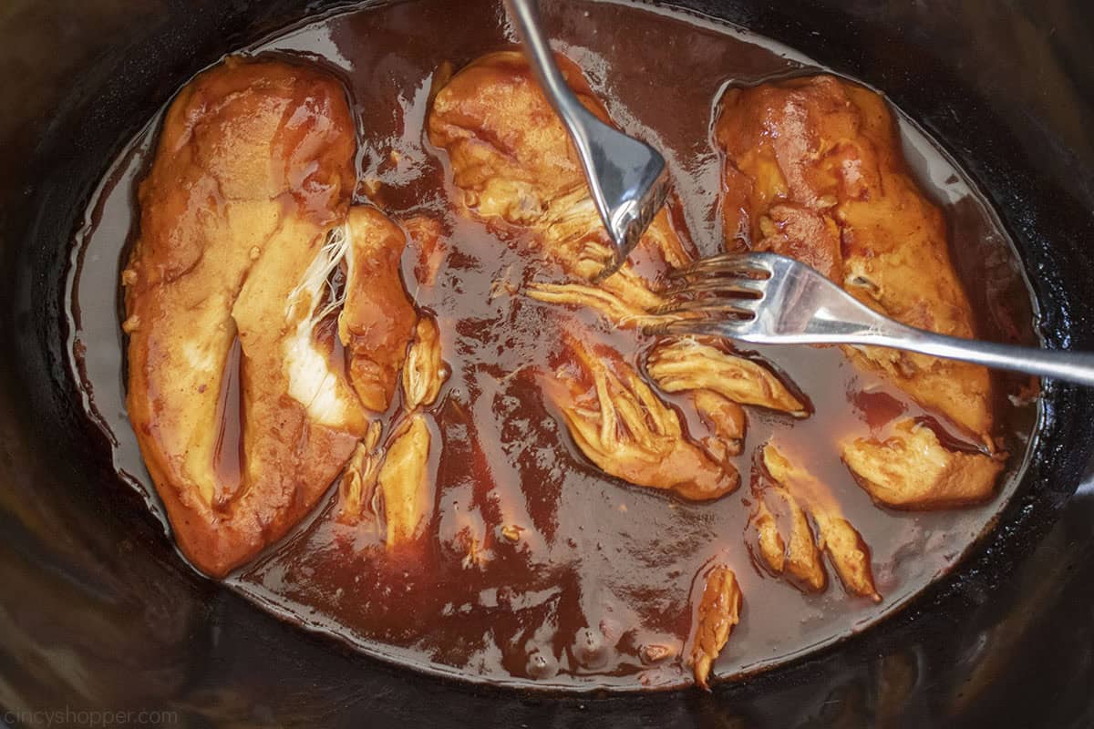 Shredded chicken with BBQ sauce and two forks.