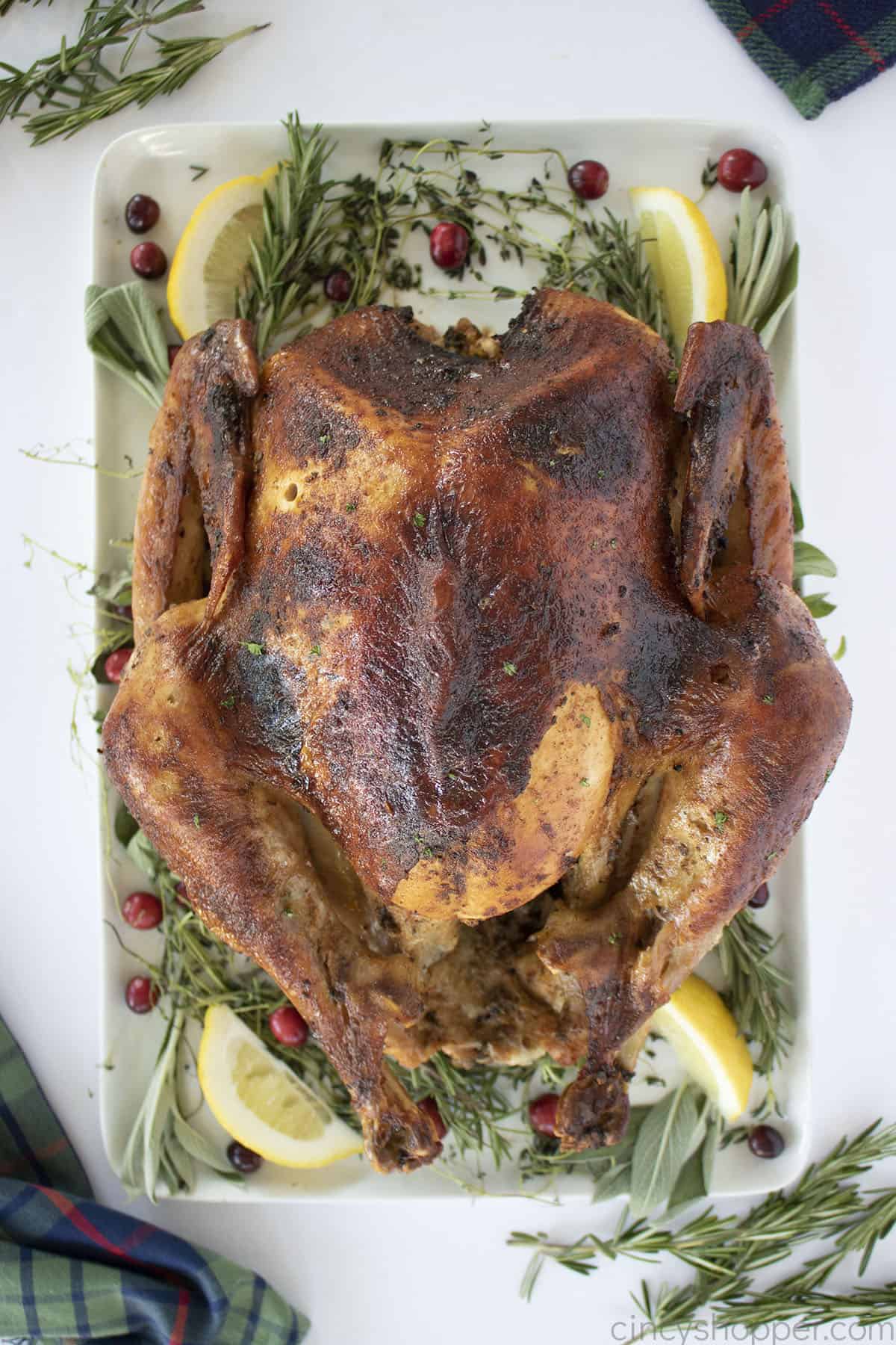 Overhead of Cajun Turkey on a rectangular platter with lemons, herbs and cranberries.