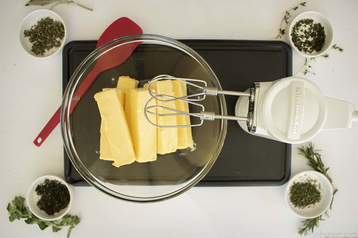 Clear mixing bowl with softened butter and hand mixer.