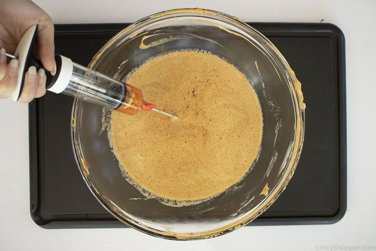 Turkey injector being filled with melted cajun butter.