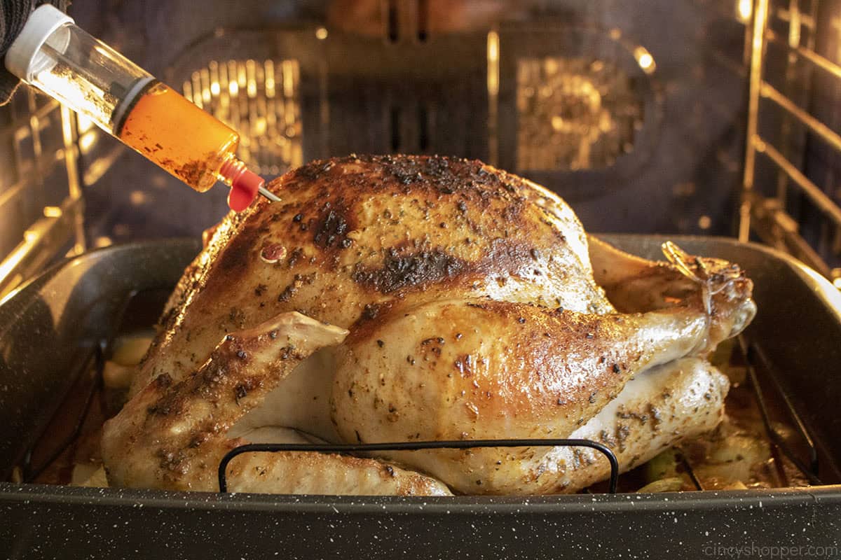 Turkey in oven with injector adding cajun butter to breast.