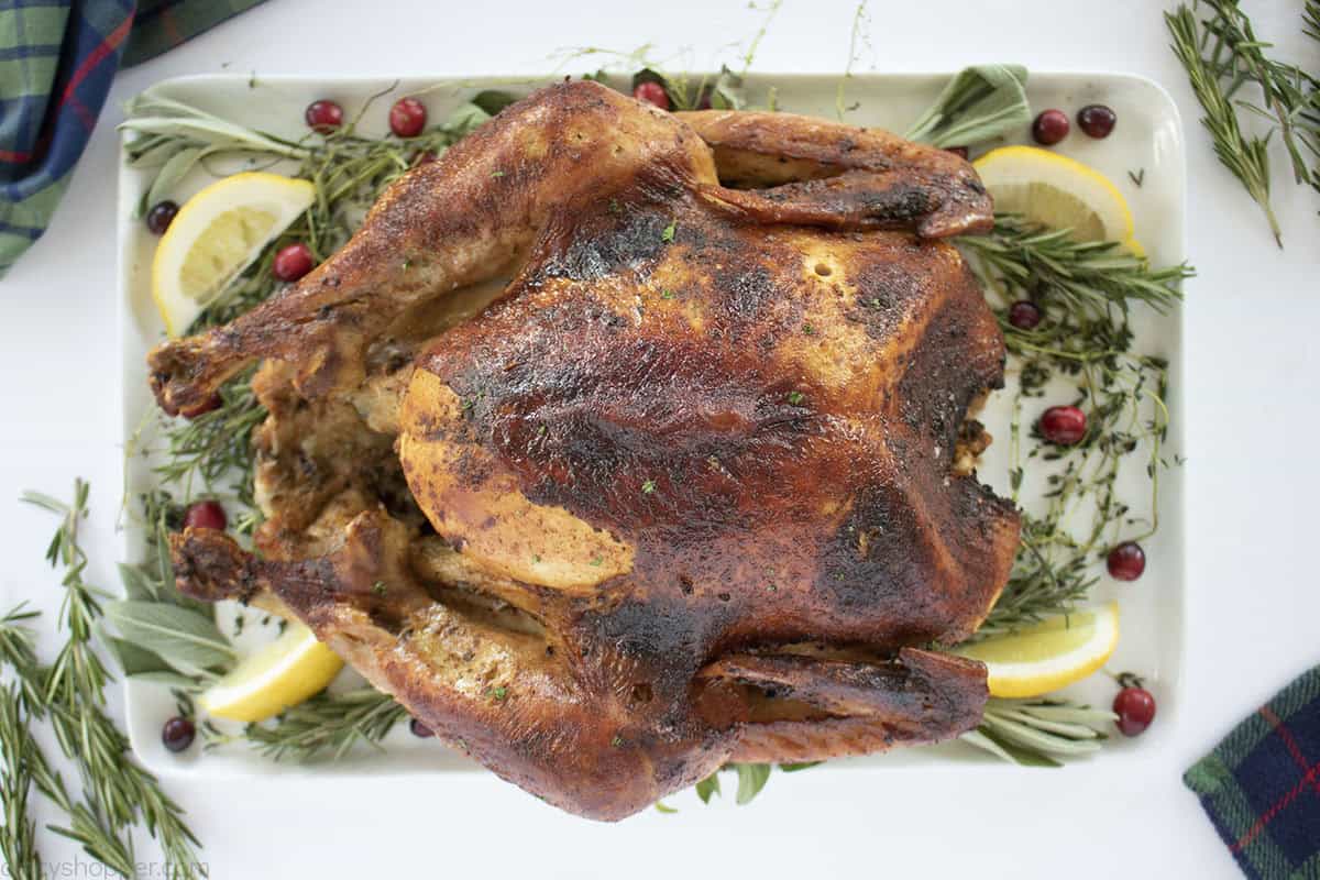 Finished oven roasted cajun turkey on a platter with fresh herbs.