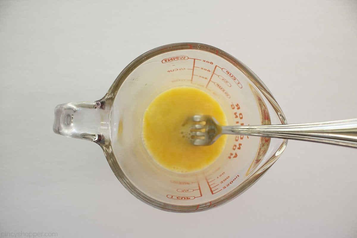 Whisked egg in a measuring cup with a fork.