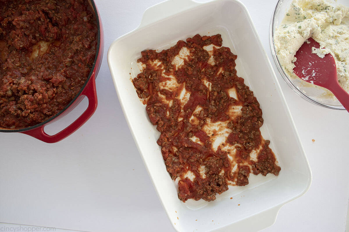 Marinara sauce in the bottom of a white casserole dish.