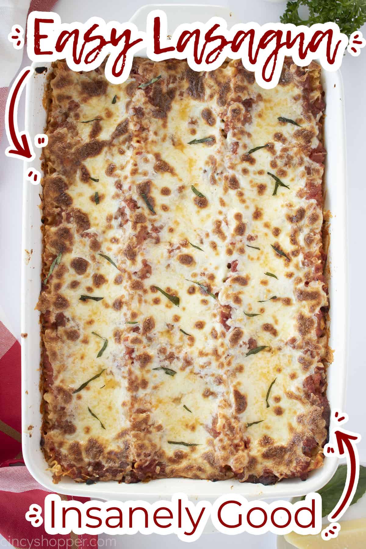 Overhead of homemade lasagna in a white baking dish with text on image - insanely good!