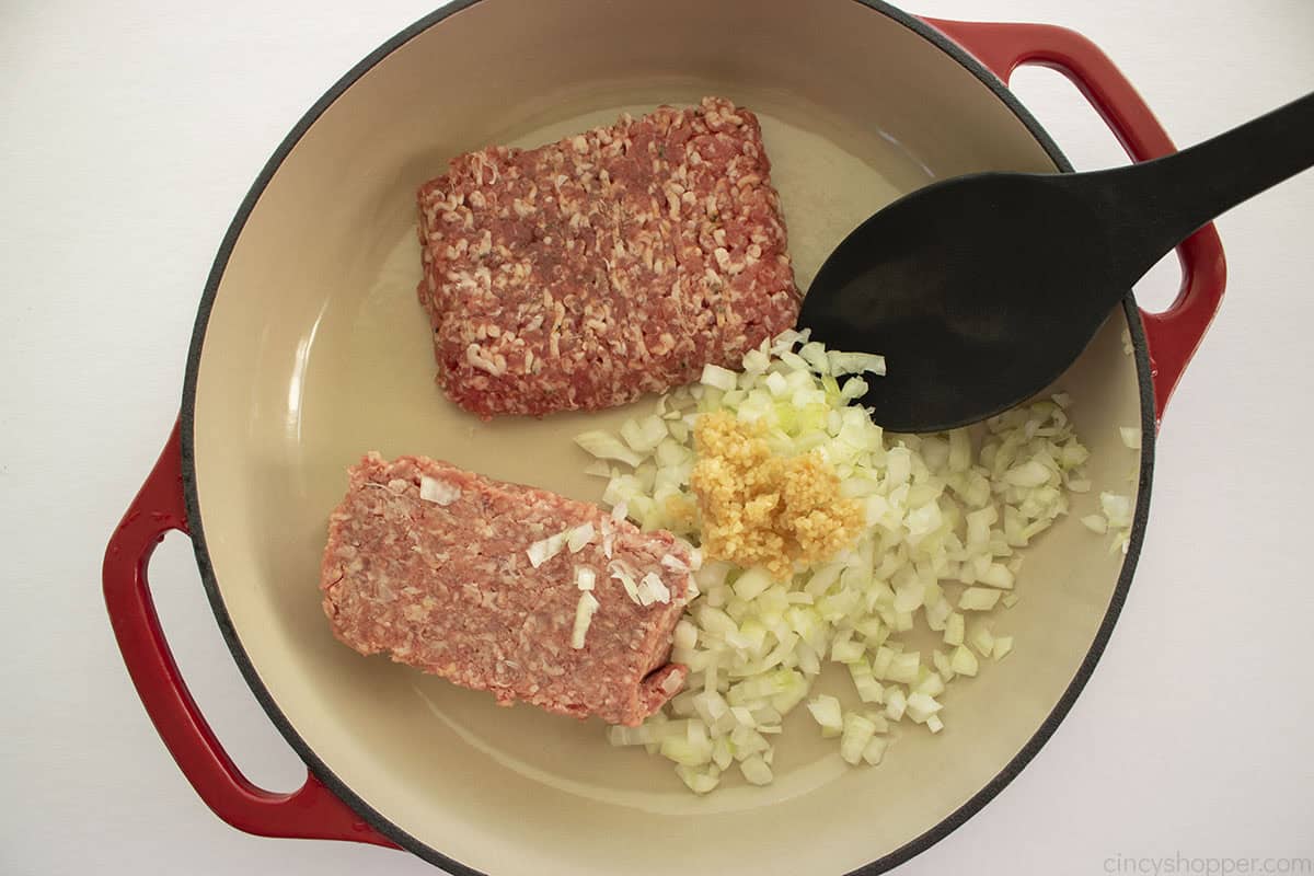 Ground beef, Italian sausage, onions and garlic in a red pan