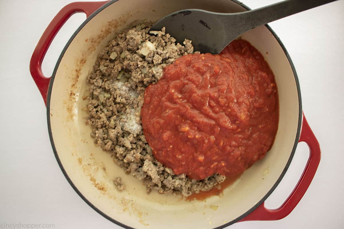 Marinara sauce added to meat mixture in pan.