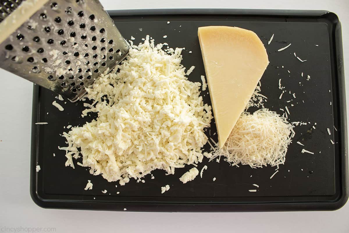 Black cutting board with cheese grater, mozzarella cheese and parmesan cheese