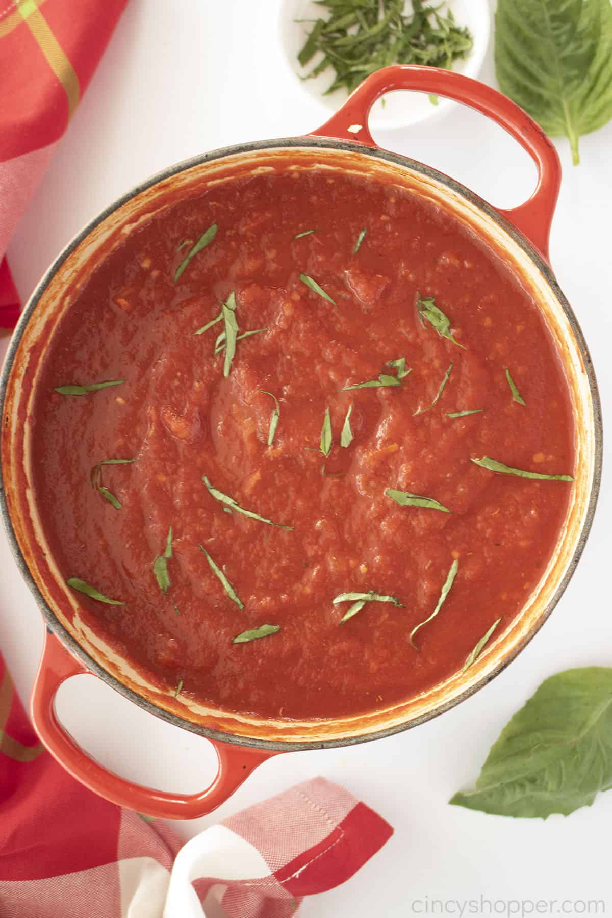 Easy Marinara Sauce in a red dutch oven with fresh basil sprinkled on top.