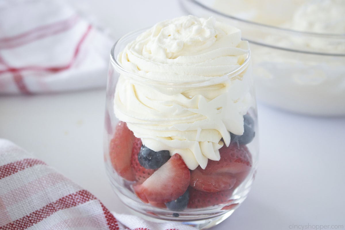 Fresh Fruit in a glass dish with homemade whipped cream.