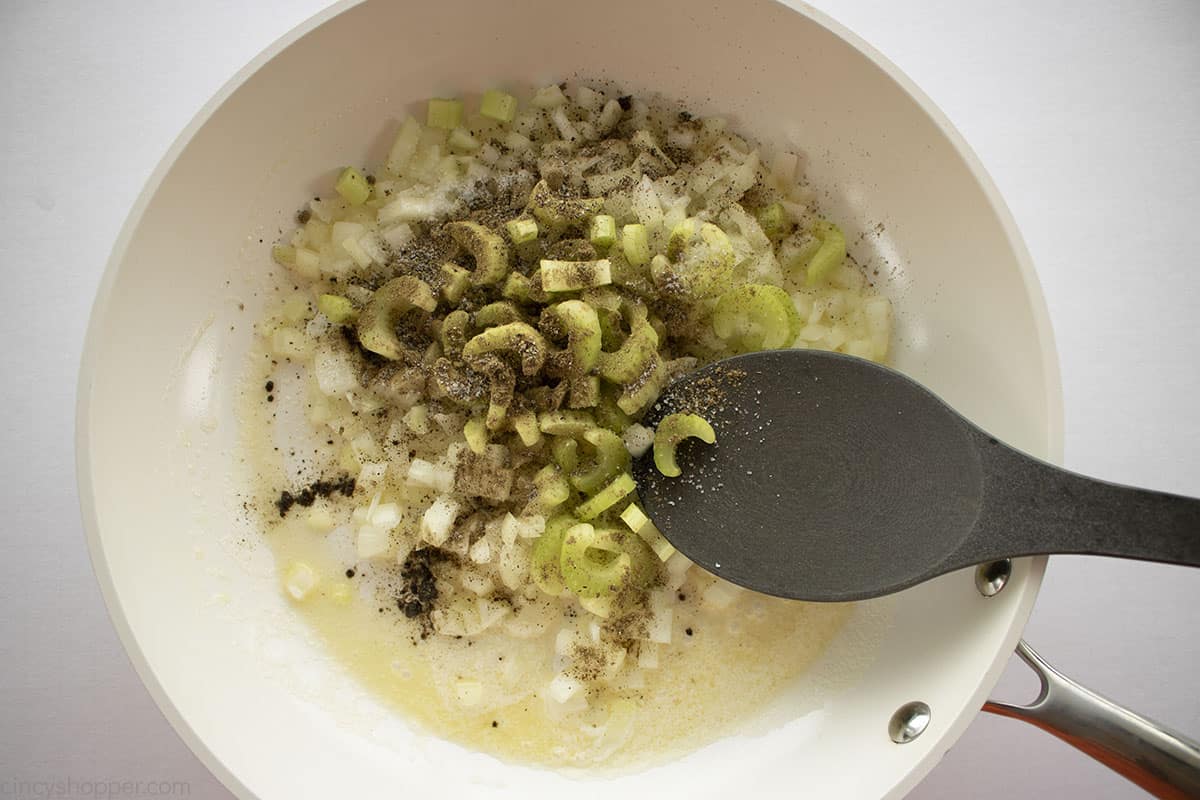 Celery onion and spices in a white pan.