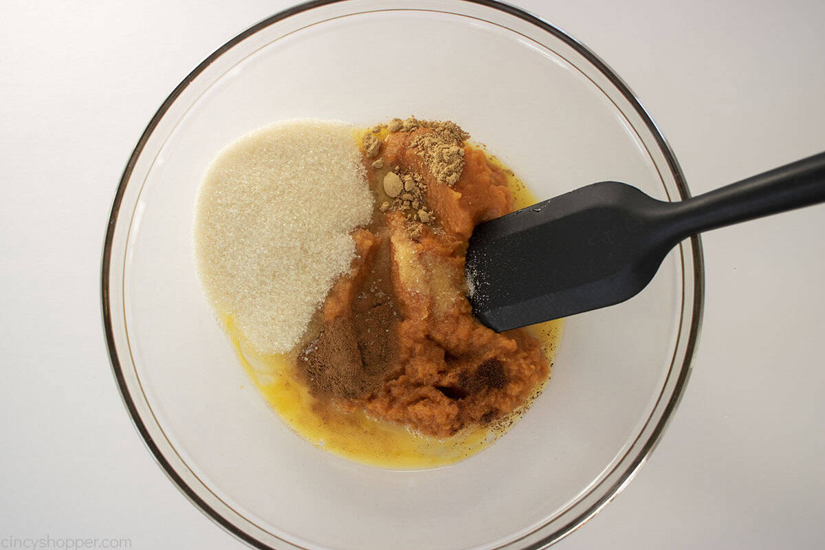 Pumpkin, sugar and spices added to a mixing bowl.