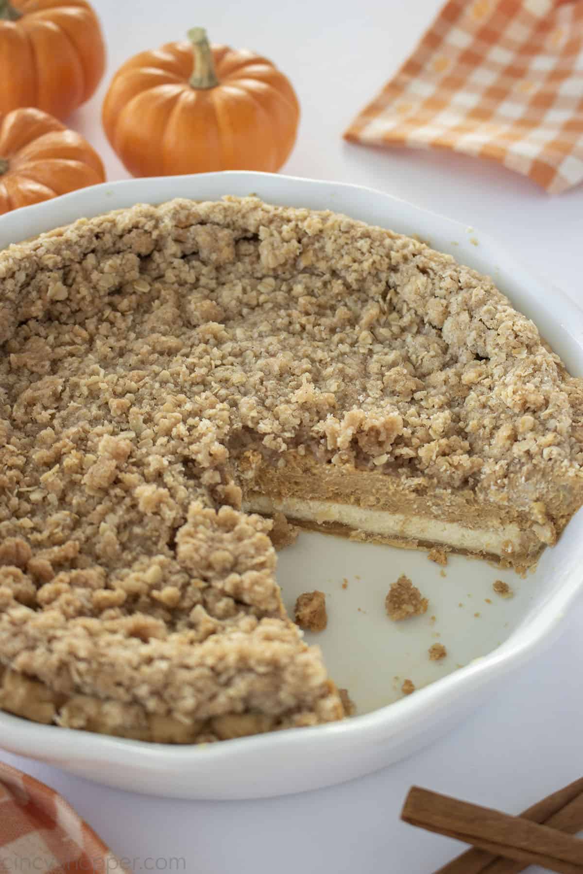 Pumpkin Cheesecake Pie in a white pie plate with one slice missing.