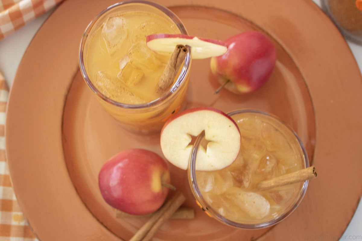 Overhead image of Thanksgiving Punch with apples and cinnamon sticks on a orange charger plate.