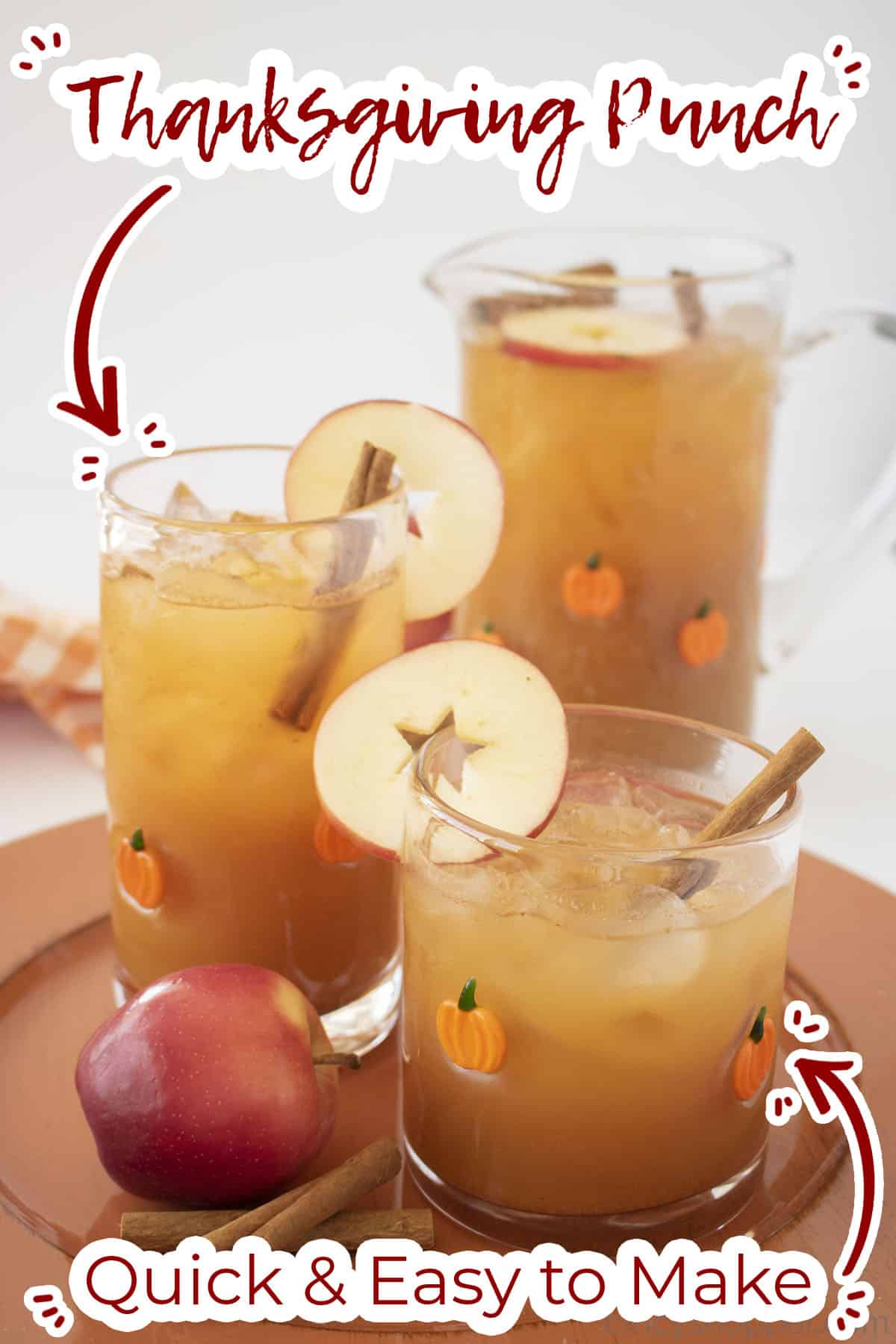 Thanksgiving Punch in two glasses and a pitcher with apples and cinnamon sticks.