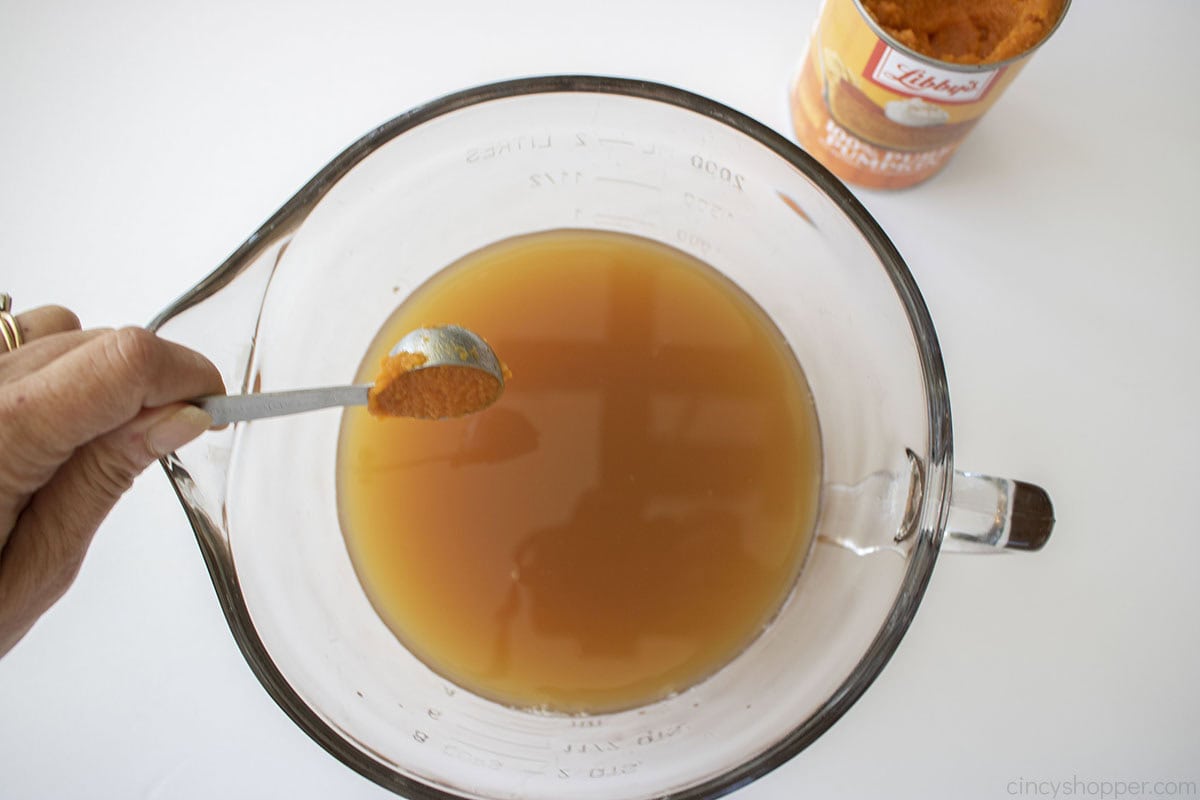 Adding pumpkin to the apple cider caramel mixture.