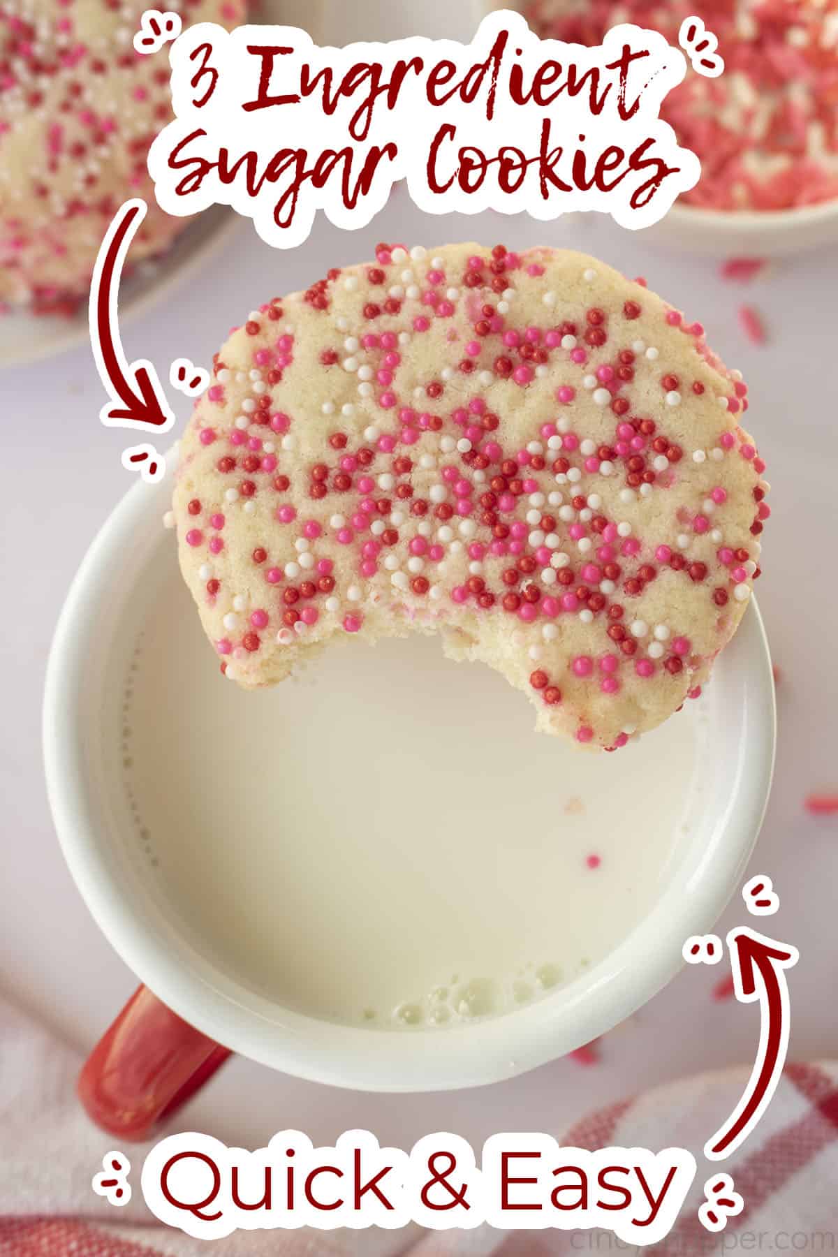 Bite taken from sugar cookie over the top of a cup with milk.