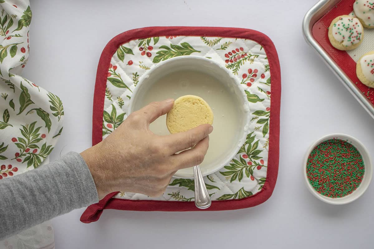 Dipping anise cookie into glaze.