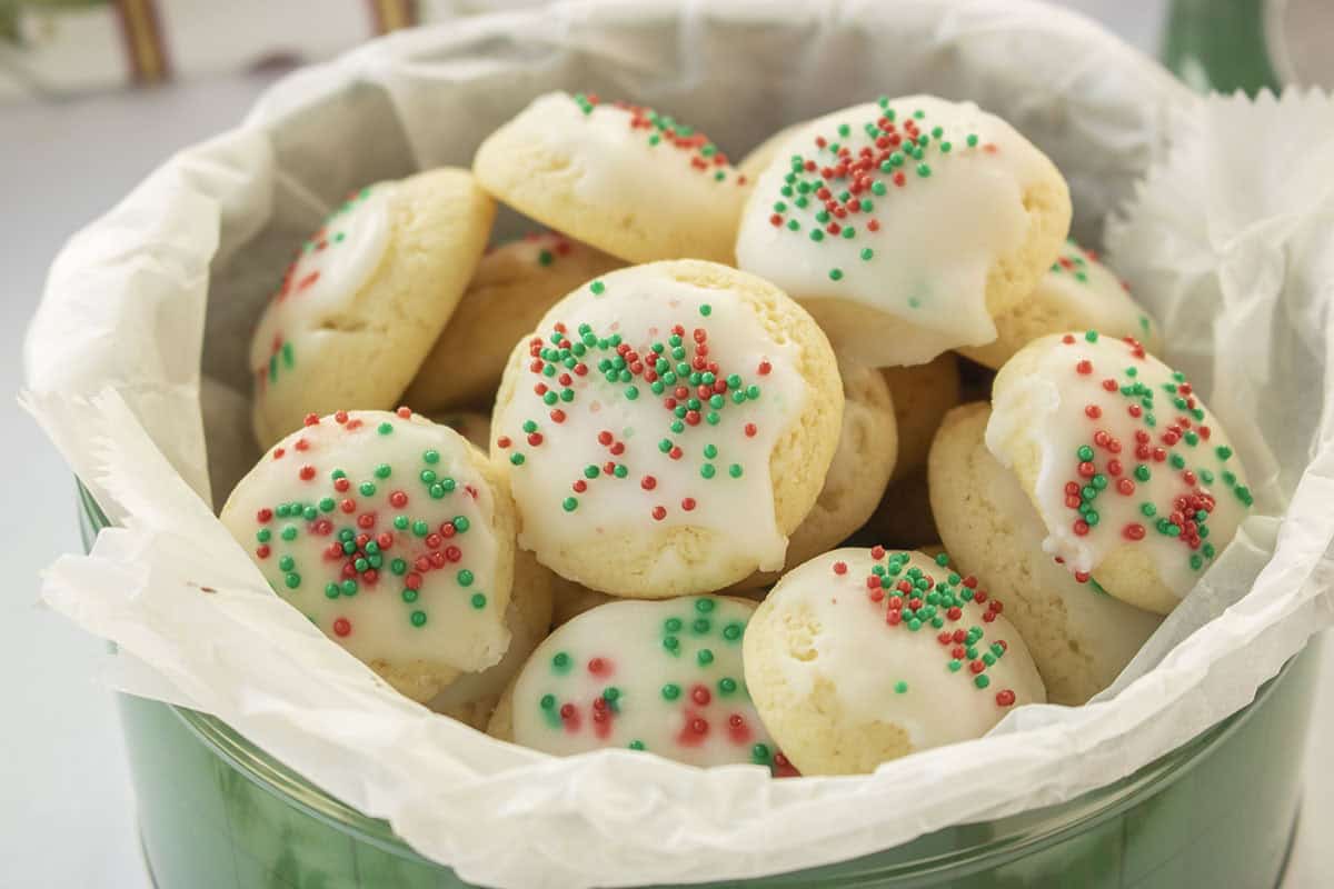 Christmas sprinkled cookies in a green cookie tin.