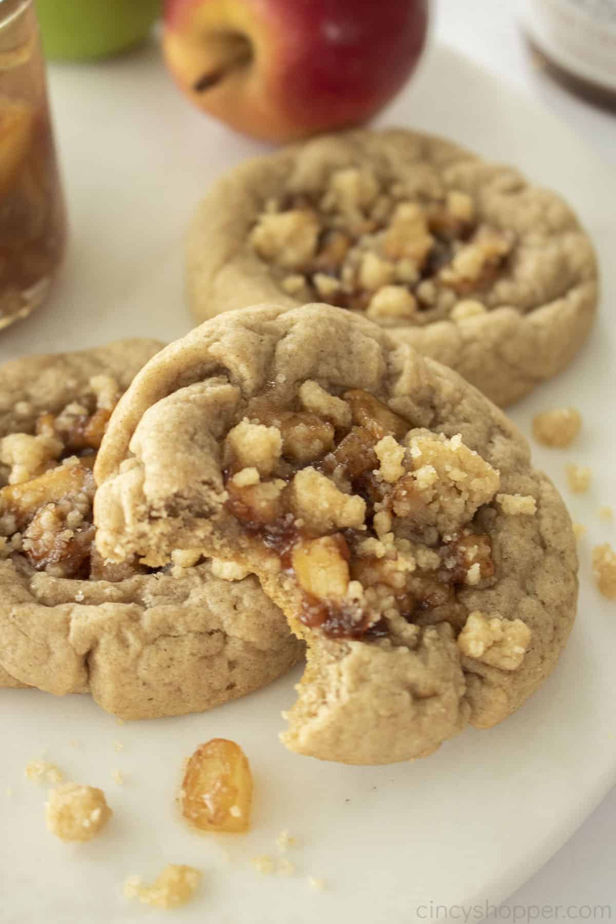 Apple Pie cookies on a white marble board with bite from one cookie.