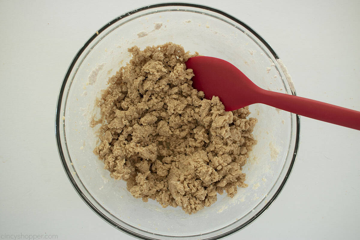 Combine apple pie cookie dough in a clear bowl with a red spatula.