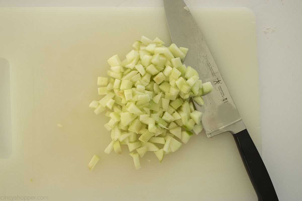 Diced green apple on a cutting board with a knife.