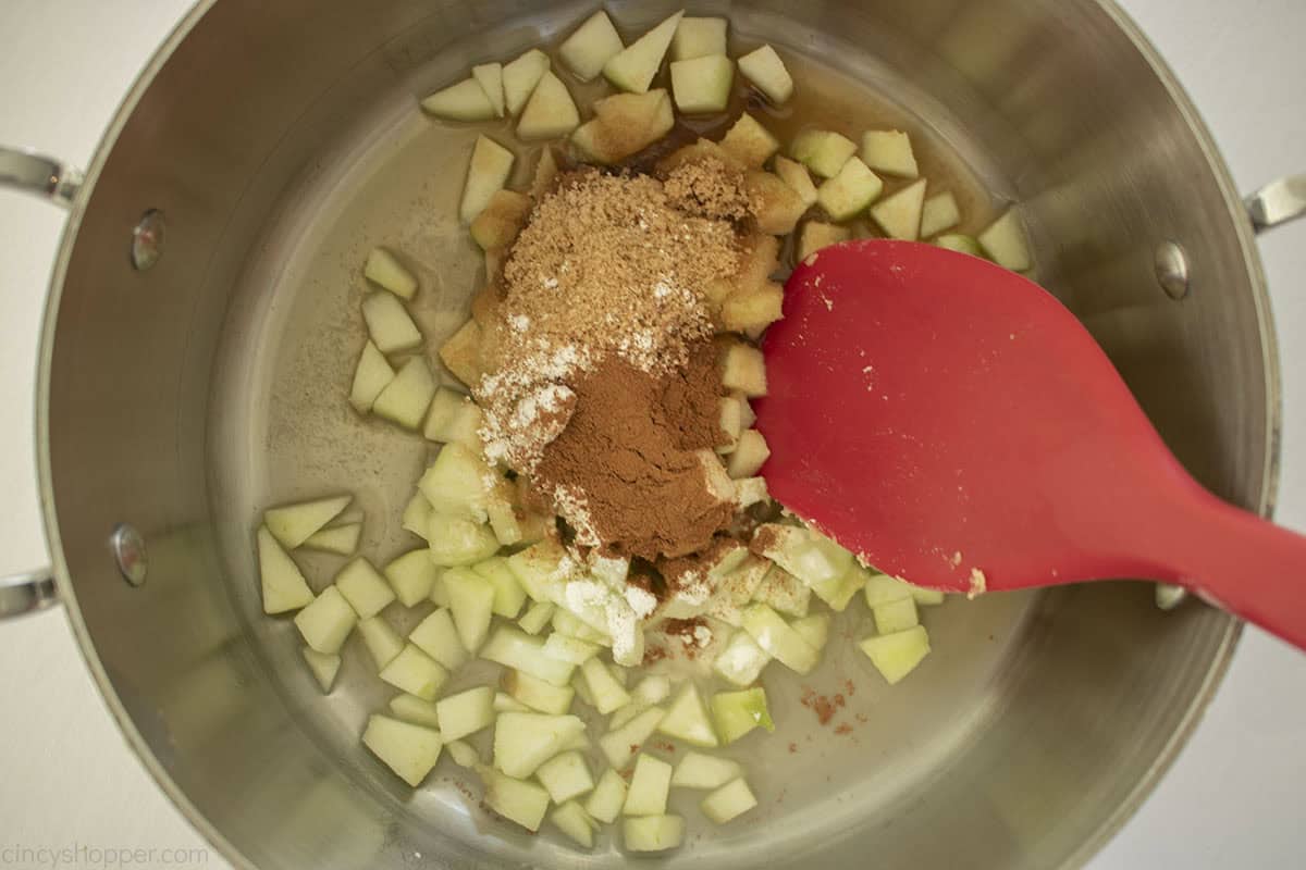 Apple Pie filling ingredients in a pan with a red spatula.