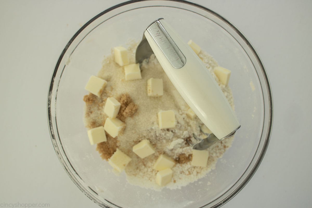 Streusel Crumb topping ingredients in a clear mixing bowl with a pastry cutter.